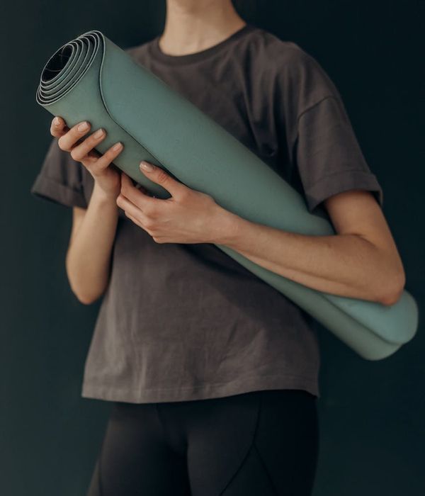 Woman in a calm, focused yoga posture in a bright, minimalist room.